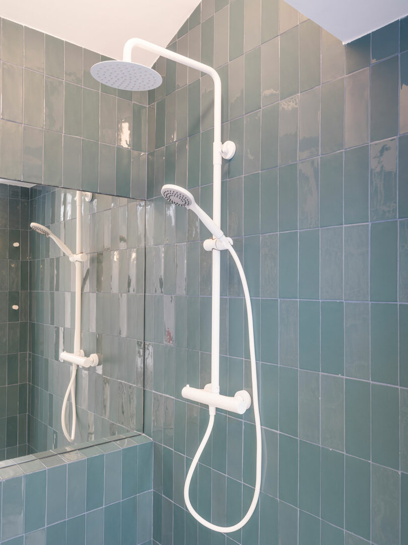 Modern bathroom interior with a teal tiled wall featuring a white dual shower system.