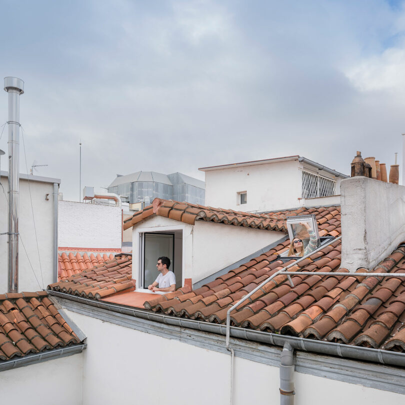 rooftop view looking toward open window with man standing looking out