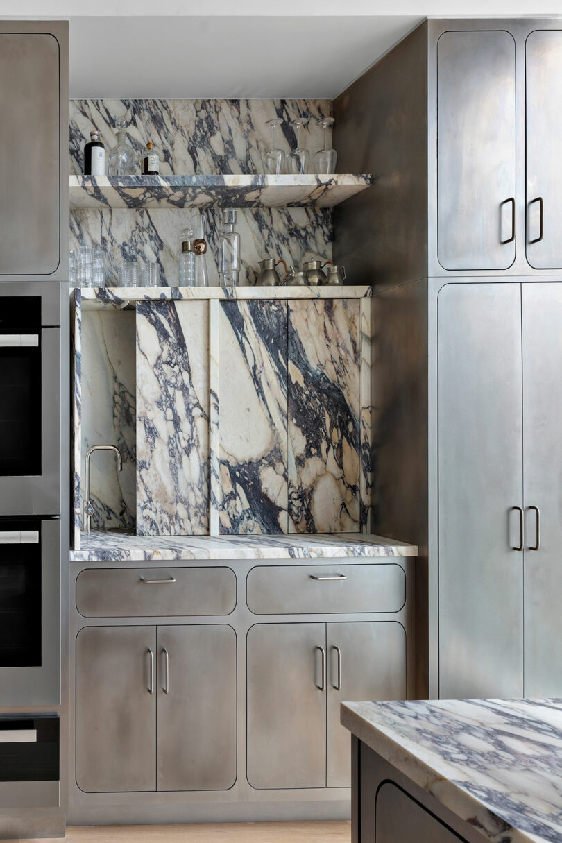 A modern kitchen with stainless steel cabinets and appliances, featuring a Rockhill marble backsplash and countertop.