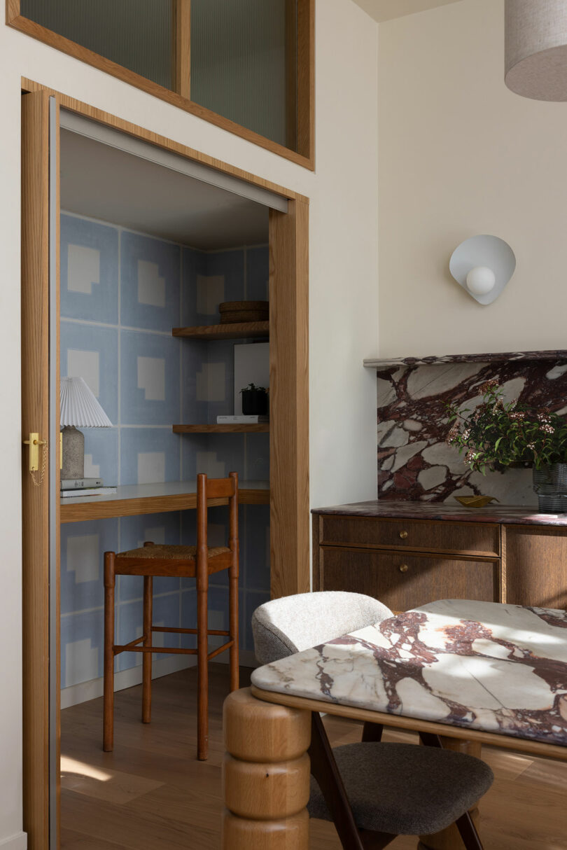 Interior of a stylish room featuring a marble table, patterned blue cupboard, and a wooden chair, with elegant decor elements and ambient lighting.