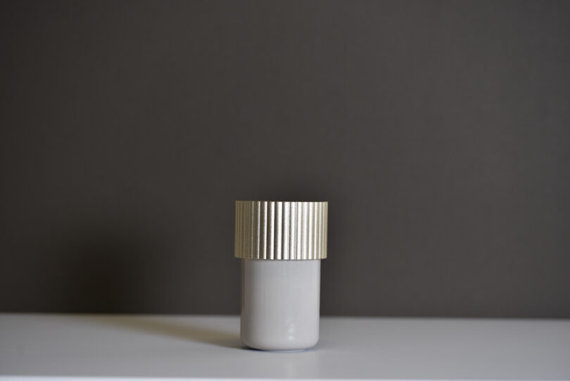 a storage box bathroom accessory with a gold cap on a grey table