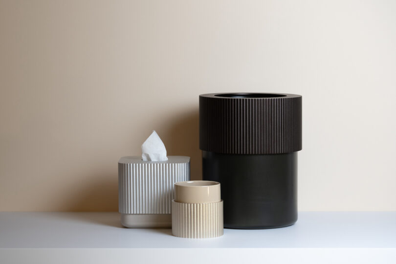 metal tissue box, a black storage box, and a beige storage box on a table