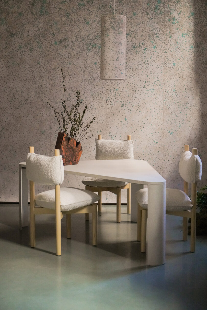 Three white, fluffy chairs with wooden legs beside a table.