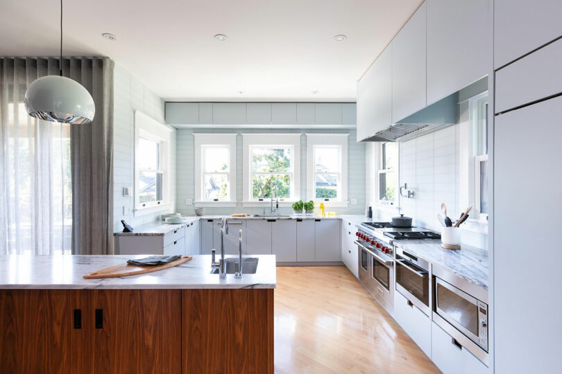 Modern kitchen interior with white cabinetry, wooden island, and stainless steel appliances. Bright space with natural light.