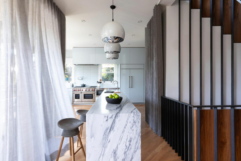 Modern kitchen with a marble island, stainless steel appliances, and wooden floors.